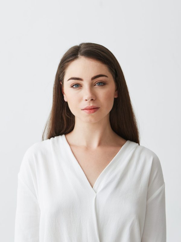 Portrait of young beautiful businesswoman looking at camera smiling over white background. Copy space.